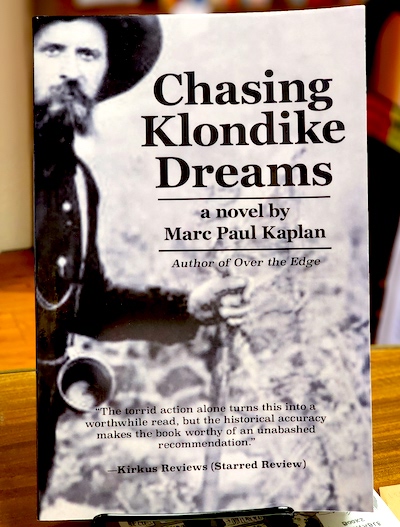 Book cover: Chasing Klondike Dreams by Marc Paul Kaplan, with antique image of pioneer with outdoor clothing and gear.