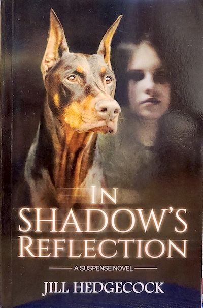Book cover: In Shadow's Reflection with image of a Doberman looking forward with perked ears, and blurred image of a girl's face behind him.